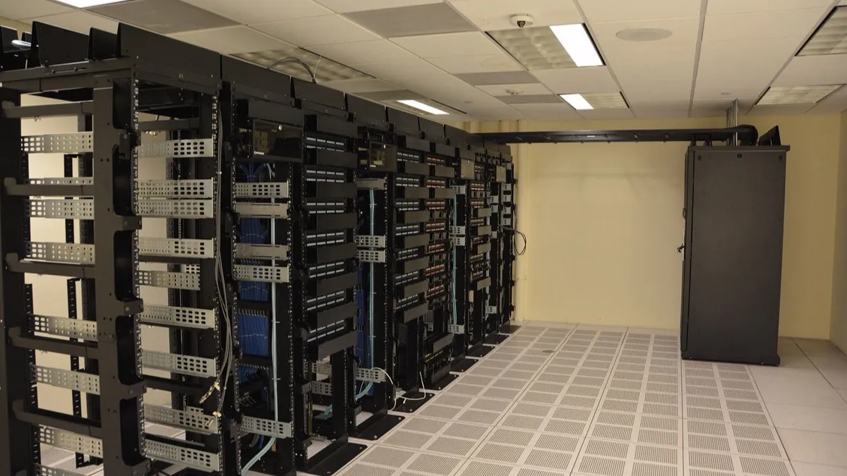 Hileras de racks de servidores en un centro de datos, con cables de red y luces de estado