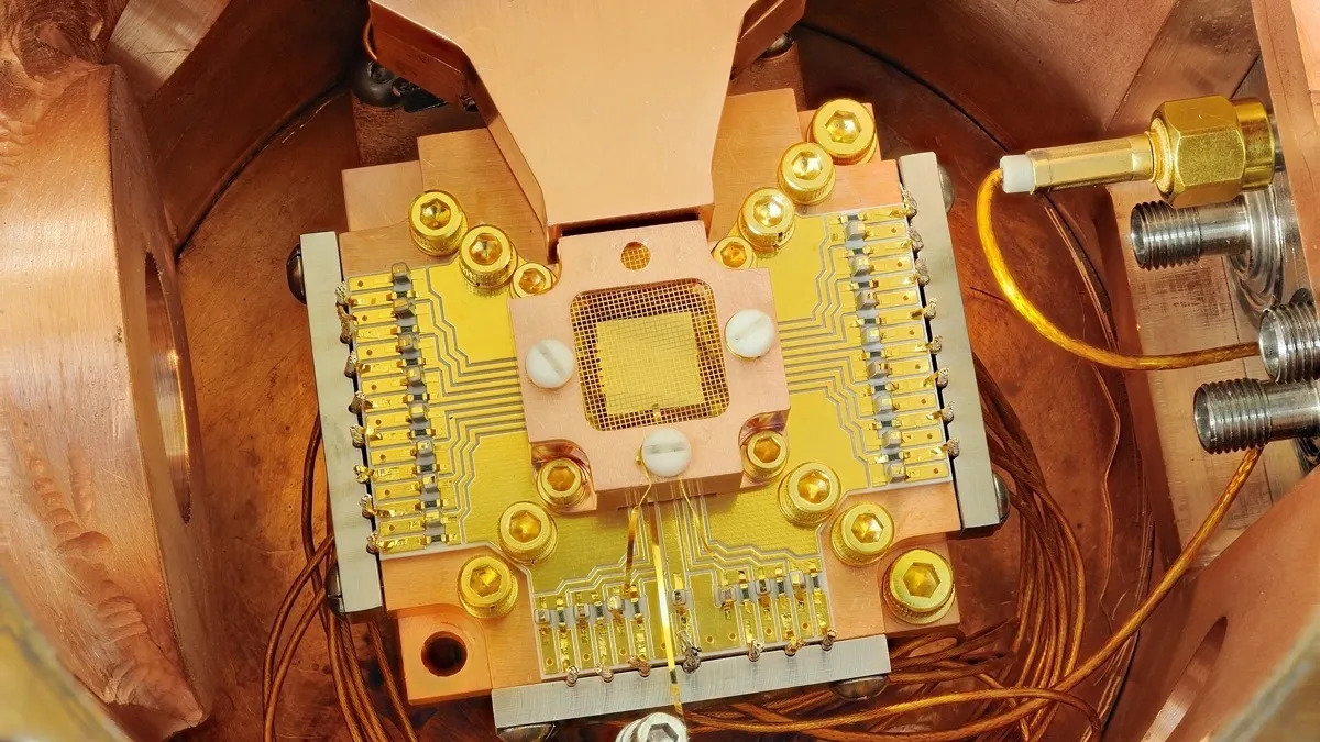 NIST ion trap chip mounted on a copper holder with gold contacts