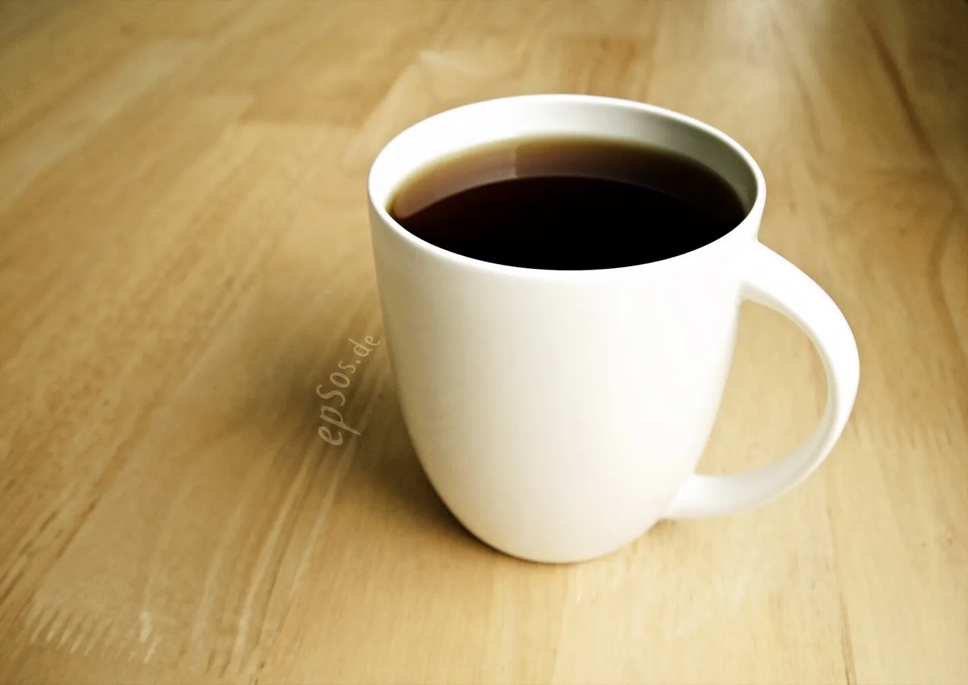 White cup of steaming black coffee on a surface