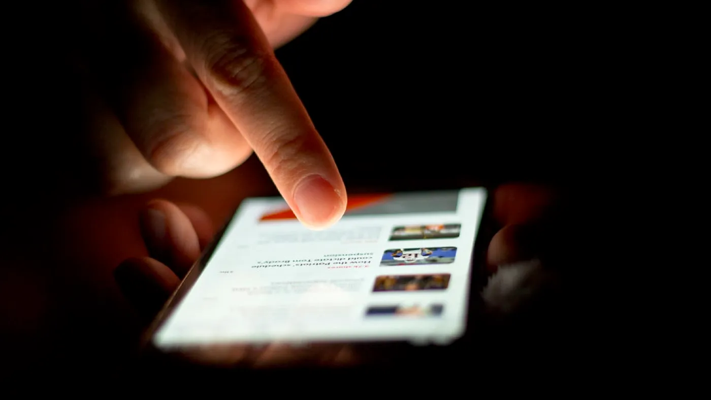 Mano sosteniendo un teléfono móvil mientras se desplaza por la pantalla